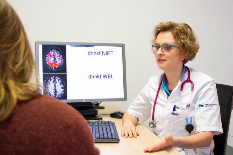 Header van dokter die naast computerscherm zit